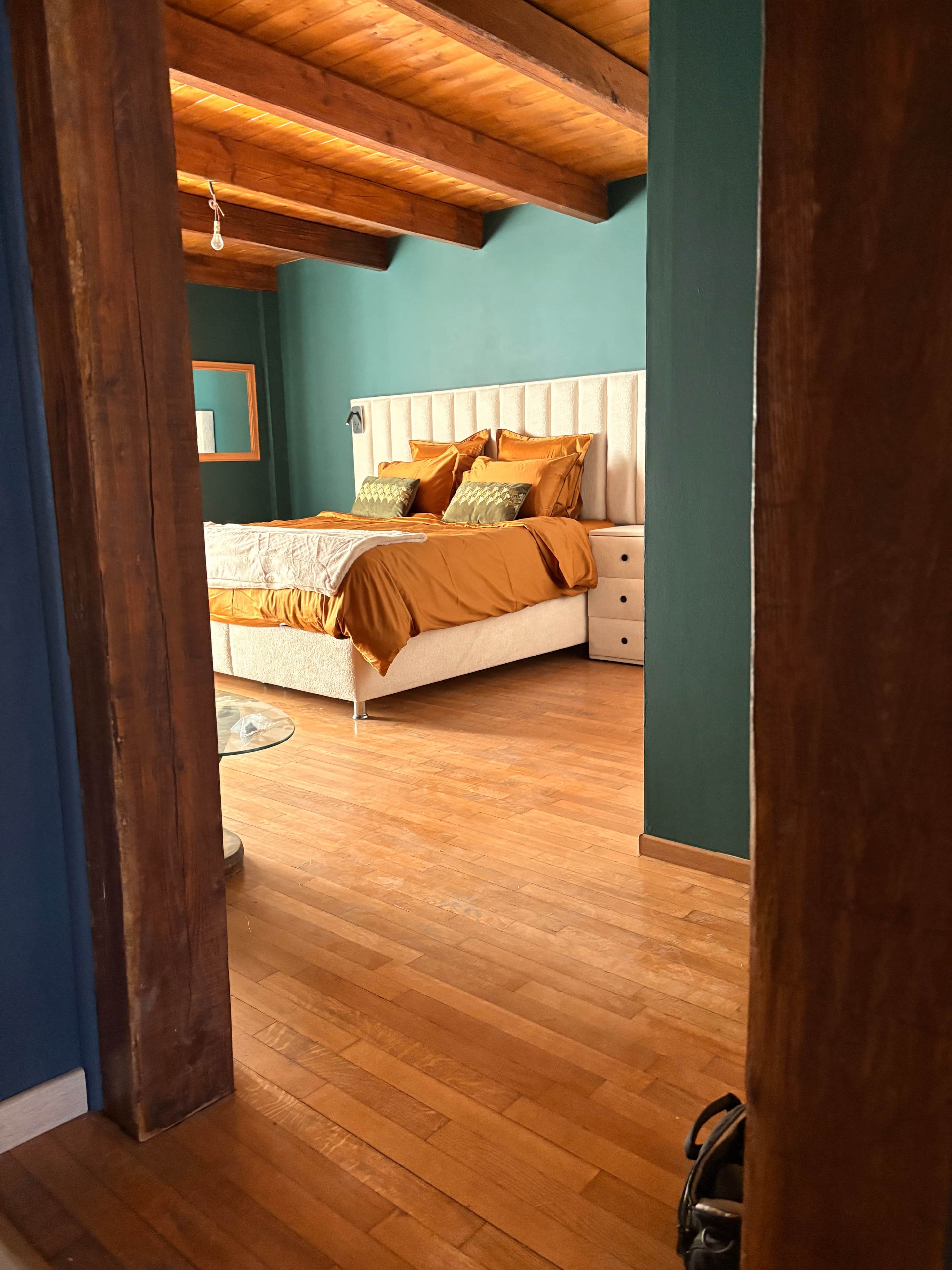 Un dormitorio con techo de madera, una cama con ropa de cama naranja y una mesita de noche.