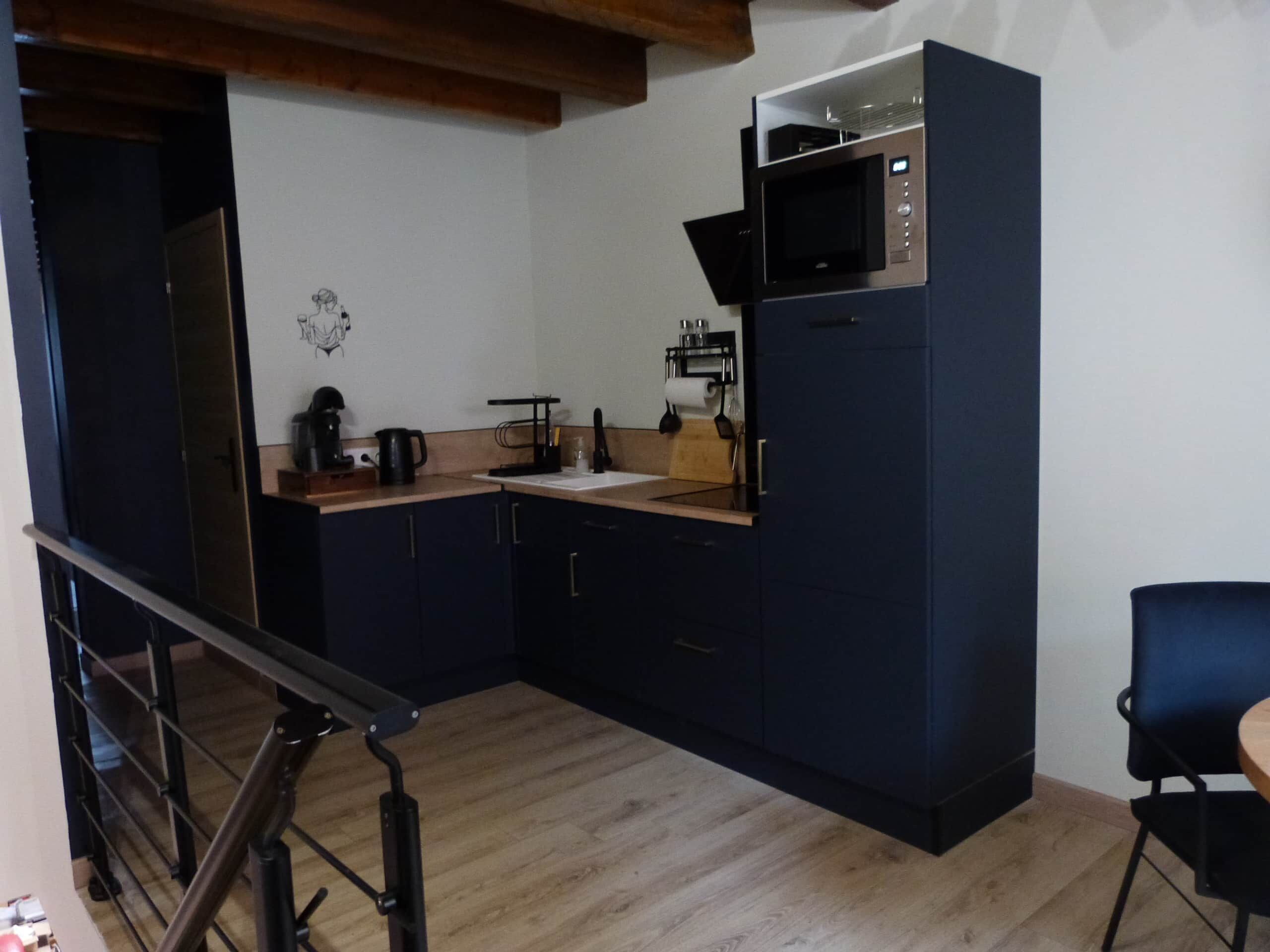 Een compacte keuken met donkere kastjes, een magnetron, een koffiezetapparaat en een klein aanrecht.