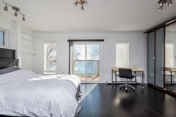 Quarto com cama, escrivaninha e vista para o exterior.