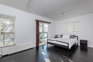 Un dormitorio con cama, mesita de noche, radiador y ventana con persianas.