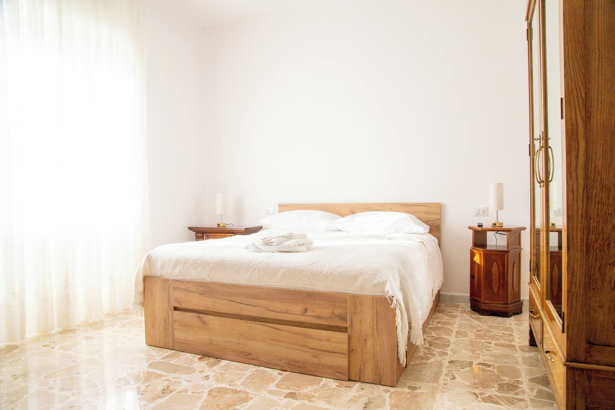 Un dormitorio con cama de madera, una mesita de noche, un armario y suelo de piedra.