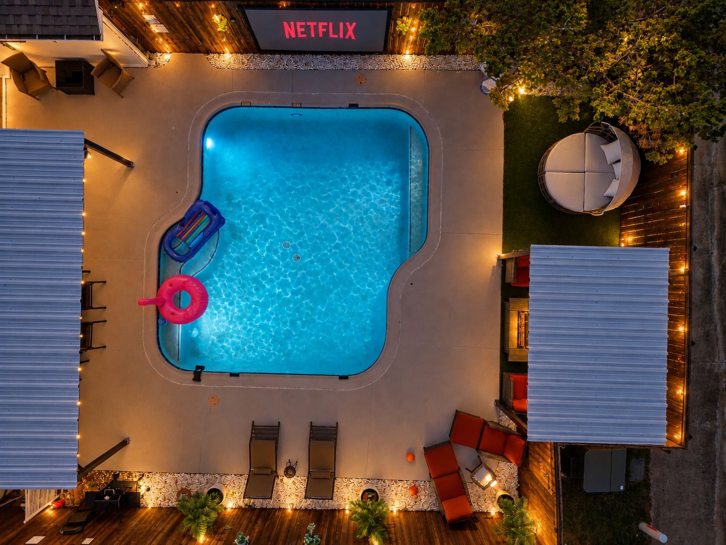 A rooftop pool area with a sign for Netflix, lounge chairs, and a covered seating area.