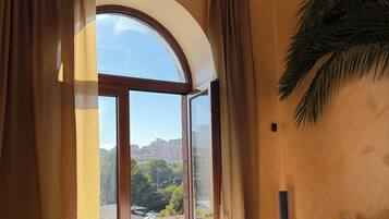 A room with a large window, a sofa, and a view of a cityscape.
