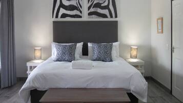 Een slaapkamer met een bed, twee nachtkastjes, een plafondventilator en wanddecoratie met een zebraprint.