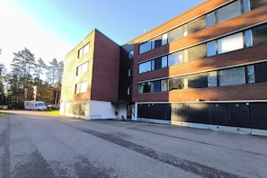 Un edificio de varios pisos con fachada de ladrillo, amplias ventanas y un estacionamiento cerrado.