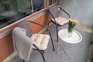 Dos sillas con cojines estampados, una mesita y un florero con flores.