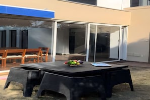 An outdoor patio with a table, chairs, and a sliding glass door leading to a covered area. - Villa Yaya (Hammamet)