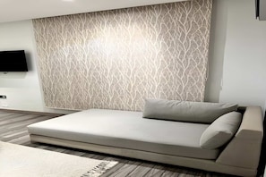 Un dormitorio moderno con sofá cama, pared estampada y televisor de pantalla plana.