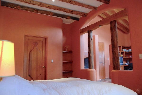 Ein Schlafzimmer mit einem Bett, Holzbalken, einer Tür und einem Bücherregal.
