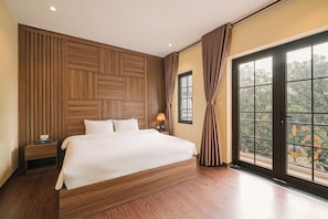 A bedroom with a large bed, wooden panel wall, a nightstand, a lamp, and a view through a window with curtains. - Park Haven Hotel (Ha Noi)