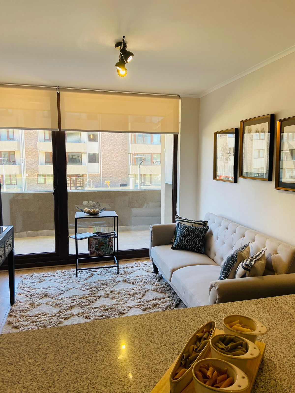 Una sala de estar moderna con un sofá, una mesa de centro y vistas a un edificio a través de amplios ventanales.