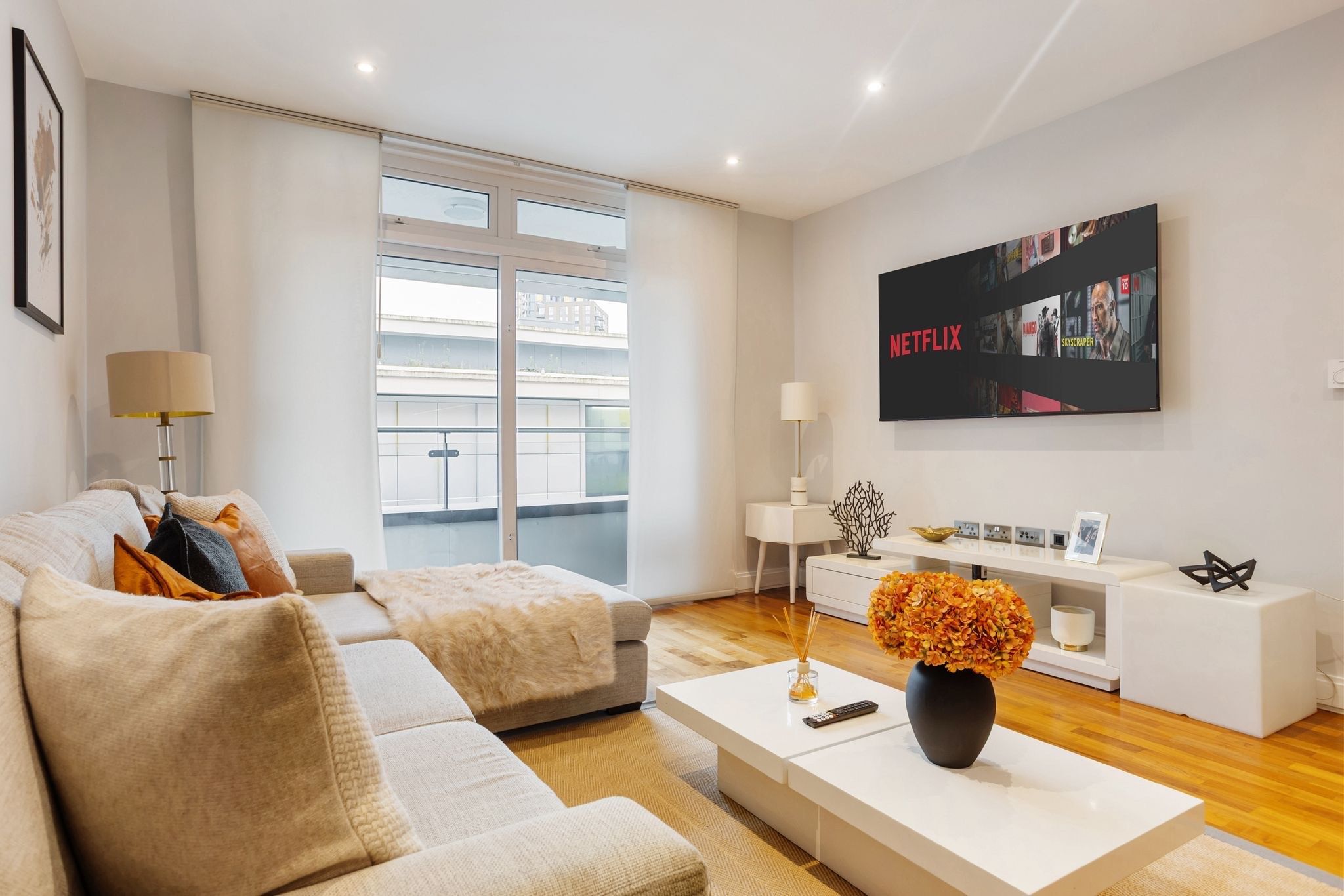 A modern living room with a sofa, coffee table, and a flat-screen TV mounted on the wall.