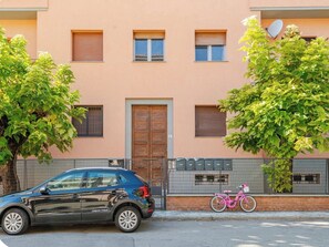 Un bâtiment à la façade beige, avec une porte en bois et un vélo rose garé devant.