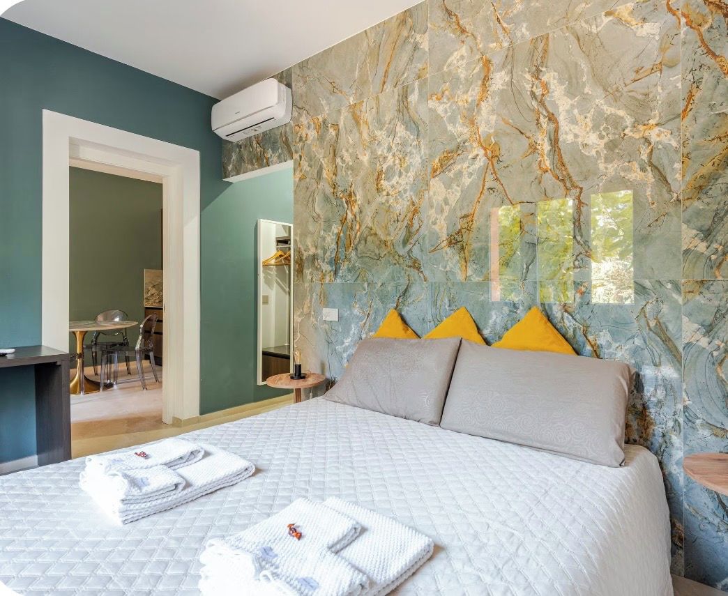 A hotel room with a bed, a bathroom, and a dining area.