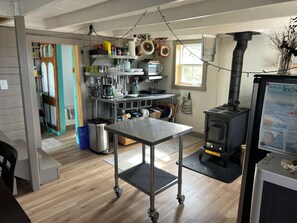 A kitchen with a central table, a stove, and various kitchen appliances. - Cozy artist's retreat with an incredible view (Keels)