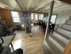 A spacious living area with a dining table, chairs, a sofa, and a staircase. - Cozy artist's retreat with an incredible view (Keels)