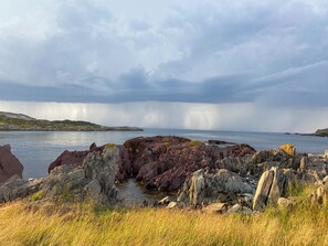 A coastal landscape with rocky terrain and a body of water. - Cozy artist's retreat with an incredible view (Keels)