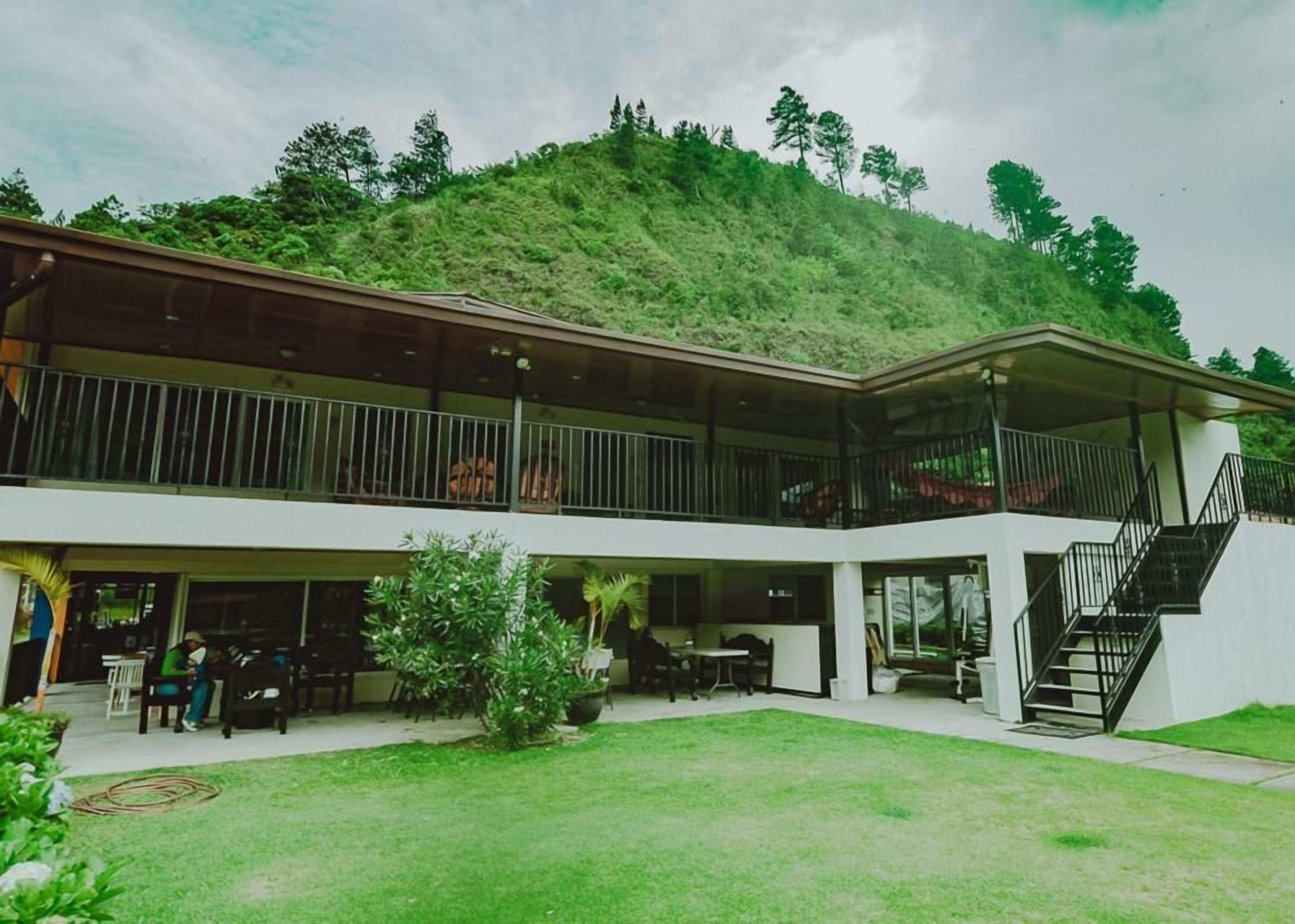 A two-story building with a covered outdoor area, a staircase, and a view of a hill.