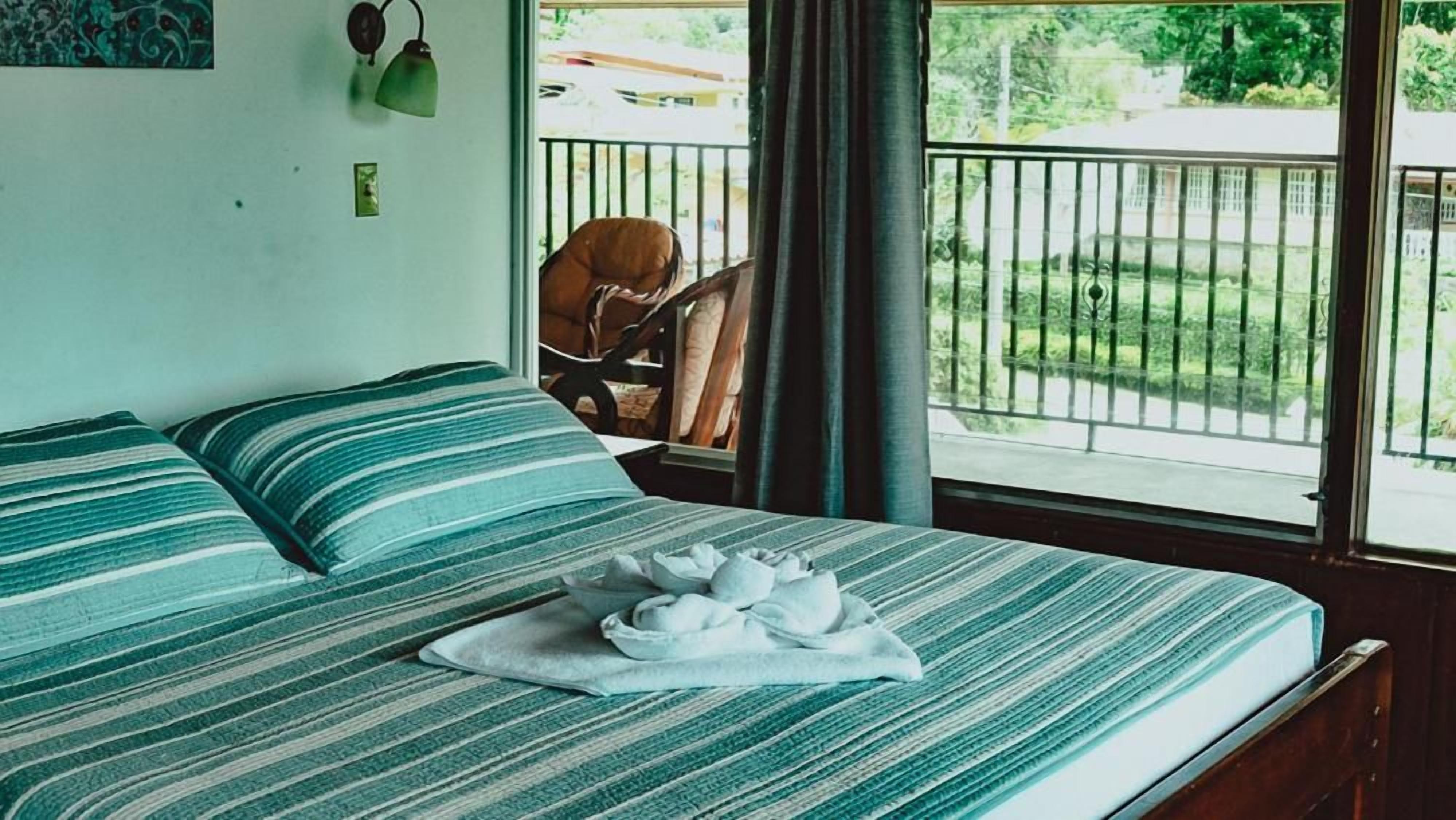 A room with two beds, a window with a view of a green landscape, and a chair outside.