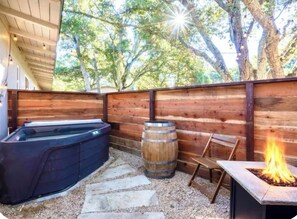 Un patio exterior con un jacuzzi, un barril, un brasero y una terraza de madera.
