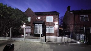 A brick house with a gated driveway and a small fenced area. - The Salford House (Salford)