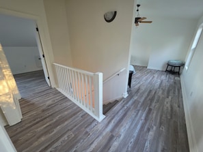 A staircase with a white railing leading to a landing, a ceiling fan, and a small table with a folded tablecloth.