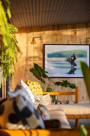 A room with a wooden ceiling, a framed picture on the wall, a sofa with cushions, and a potted plant. - House of Somos, Santa Teresa (Santa Teresa)