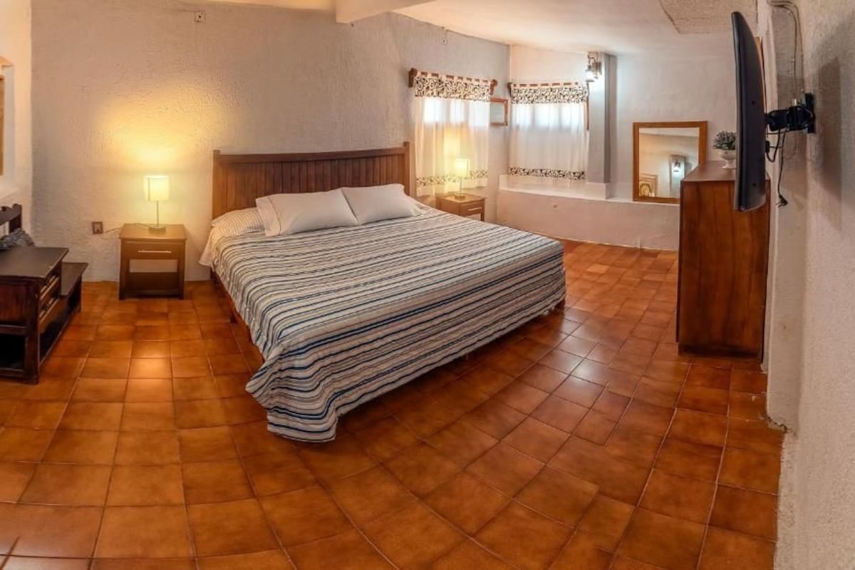 Ein Schlafzimmer mit einem Bett, Nachttischen, einem Schminktisch und einem Fernseher.
