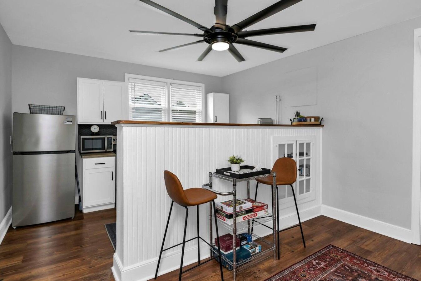 A compact kitchen with a refrigerator, microwave, and a dining area with two chairs and a small table.