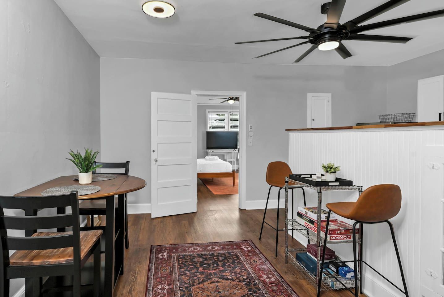 A compact living space with a dining area, a kitchenette, a bed, and a ceiling fan.