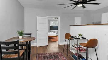 A compact living space with a dining area, a kitchenette, a bed, and a ceiling fan.