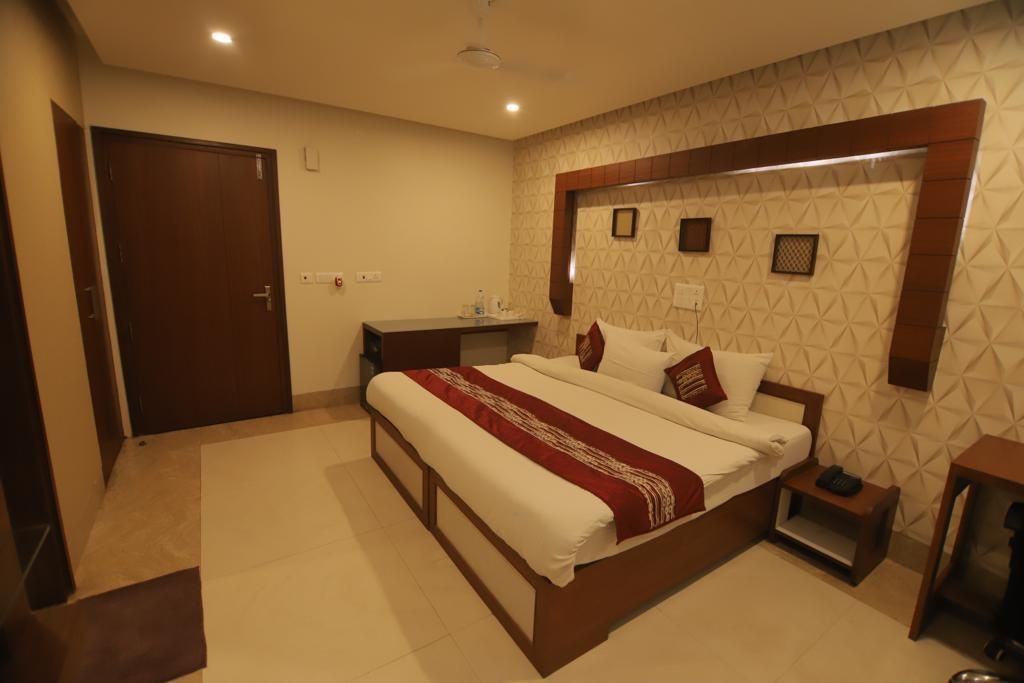 Habitación de hotel con una cama grande, mesitas de noche, armario y baño con ducha e inodoro.
