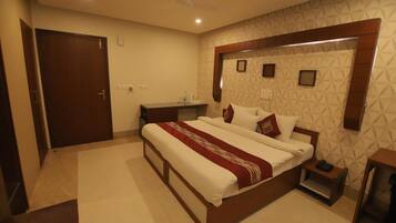 Habitación de hotel con una cama grande, mesitas de noche, armario y baño con ducha e inodoro.