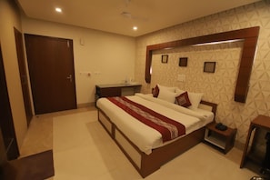 Une chambre d’hôtel avec un grand lit, des tables de chevet, une armoire et une salle de bain équipée d’une douche et de toilettes.