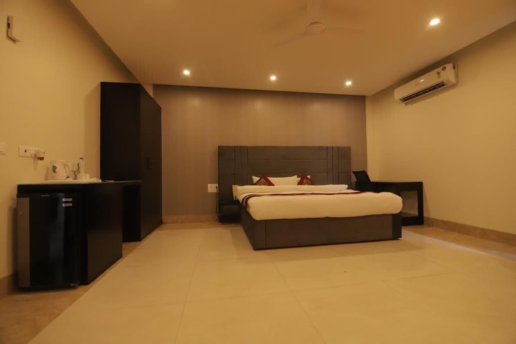 Una habitación de hotel moderna con una cama grande, una mesita de noche, un escritorio y un equipo de aire acondicionado.