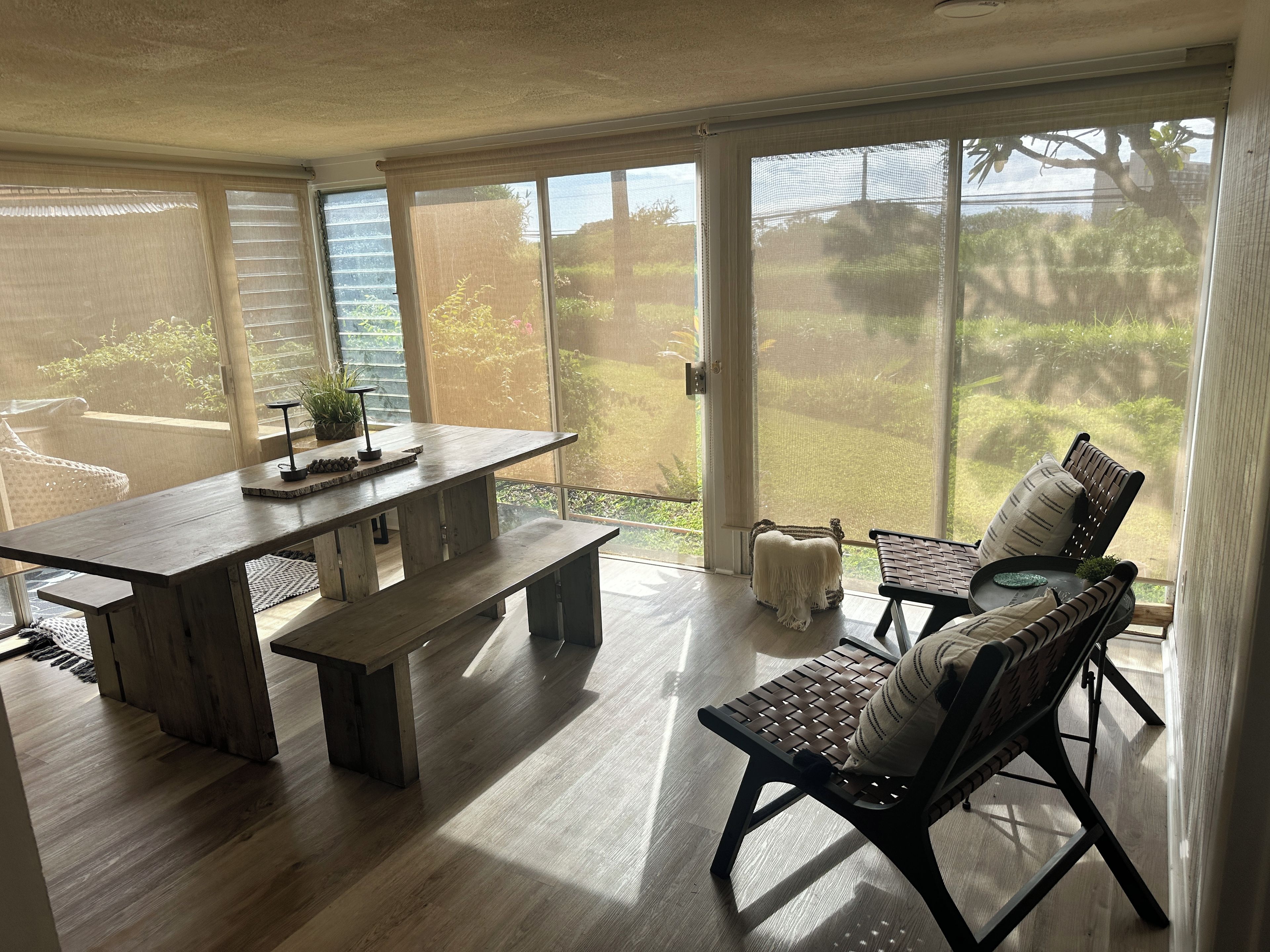 Ein geräumiges Zimmer mit einer großen Schiebetür zu einem Garten, einem Holzesstisch mit Bänken und einer Sitzgelegenheit mit Aussicht.