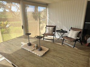 A room with a wooden table, two chairs, and a small table with a plant. - Hawaiiana  3-bedroom bungalow with AC in Kaanapali across street from beach.  (Lahaina)