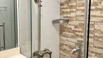 Een douche met een glazen deur, een handdouche en een bedieningspaneel op de muur.