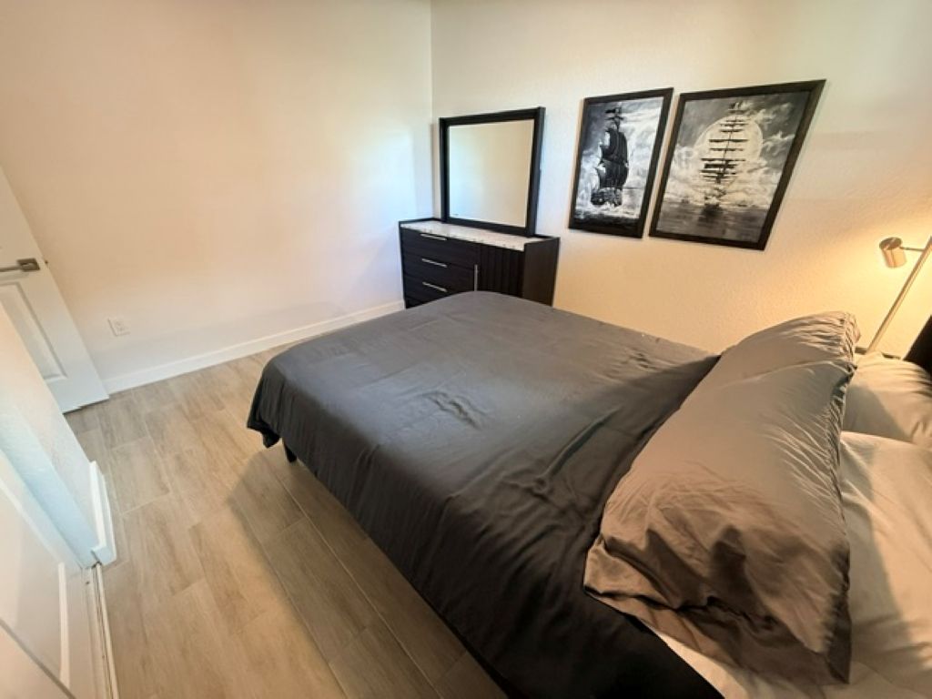 A bedroom with a bed, a dresser, and two wall-mounted artworks.