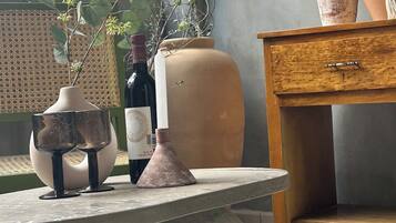 A room with a table, a potted plant, a wine bottle, and a vase.