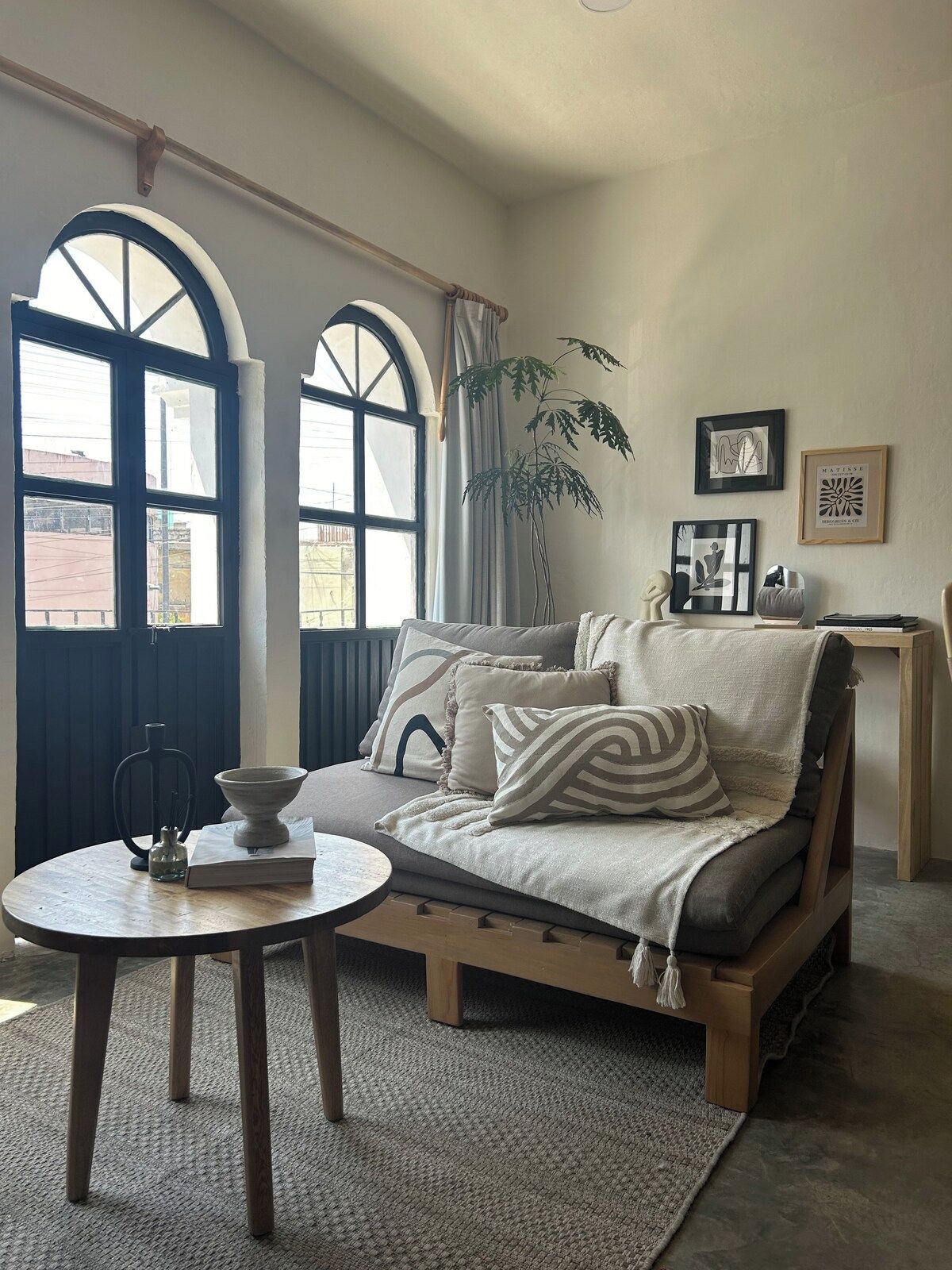 A cozy living room with a sofa, a small table, and a plant.