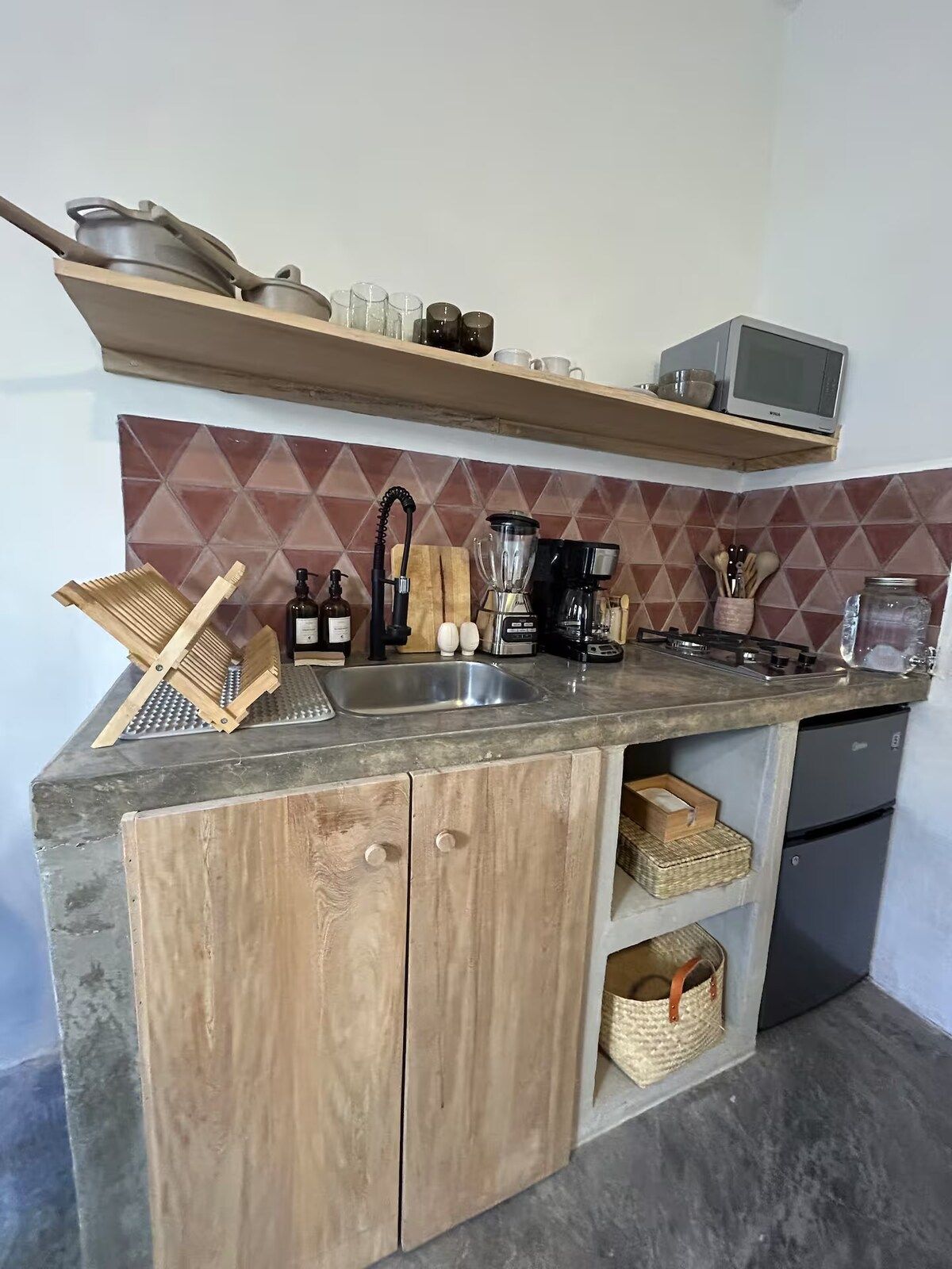 A kitchen with a wooden countertop, a sink, a microwave, and various kitchen utensils.