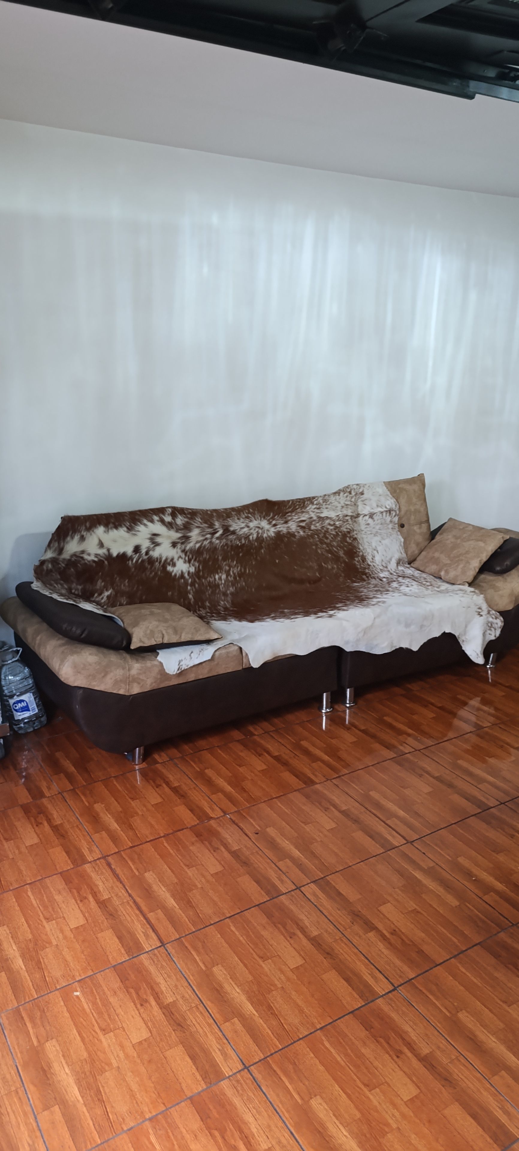 Un canapé recouvert d’un tissu à motifs, un plancher en bois et un mur blanc.