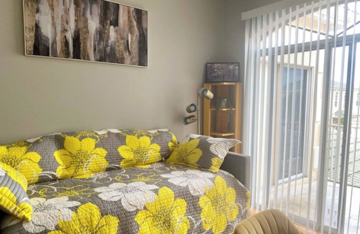 Un dormitorio con cama, un cuadro en la pared y una ventana con persianas.