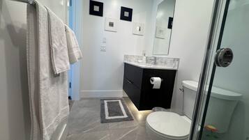A bathroom with a toilet, sink, and shower area.