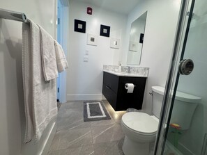 Un baño con inodoro, lavamanos y zona de ducha.
