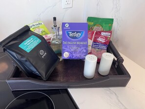 Una bandeja con una cápsula de café, una caja de té Tetley, un paquete de Splenda, una botella de agua y dos saleros.