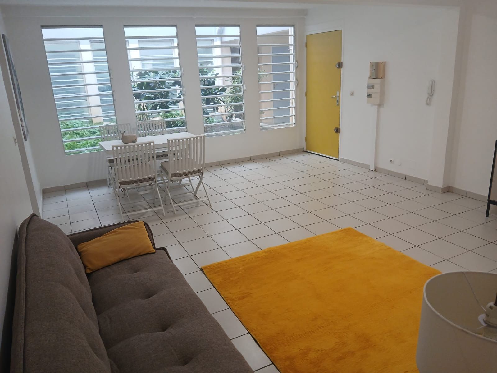 Ein Wohnzimmer mit einer Couch, einem gelben Teppich und einem Essbereich mit Tisch und Stühlen.