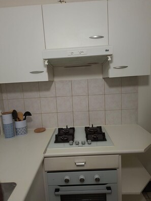 A kitchen with a gas stove, oven, and white cabinets.