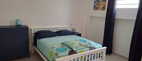 A bedroom with a bed, a dresser, a nightstand, and a painting on the wall.